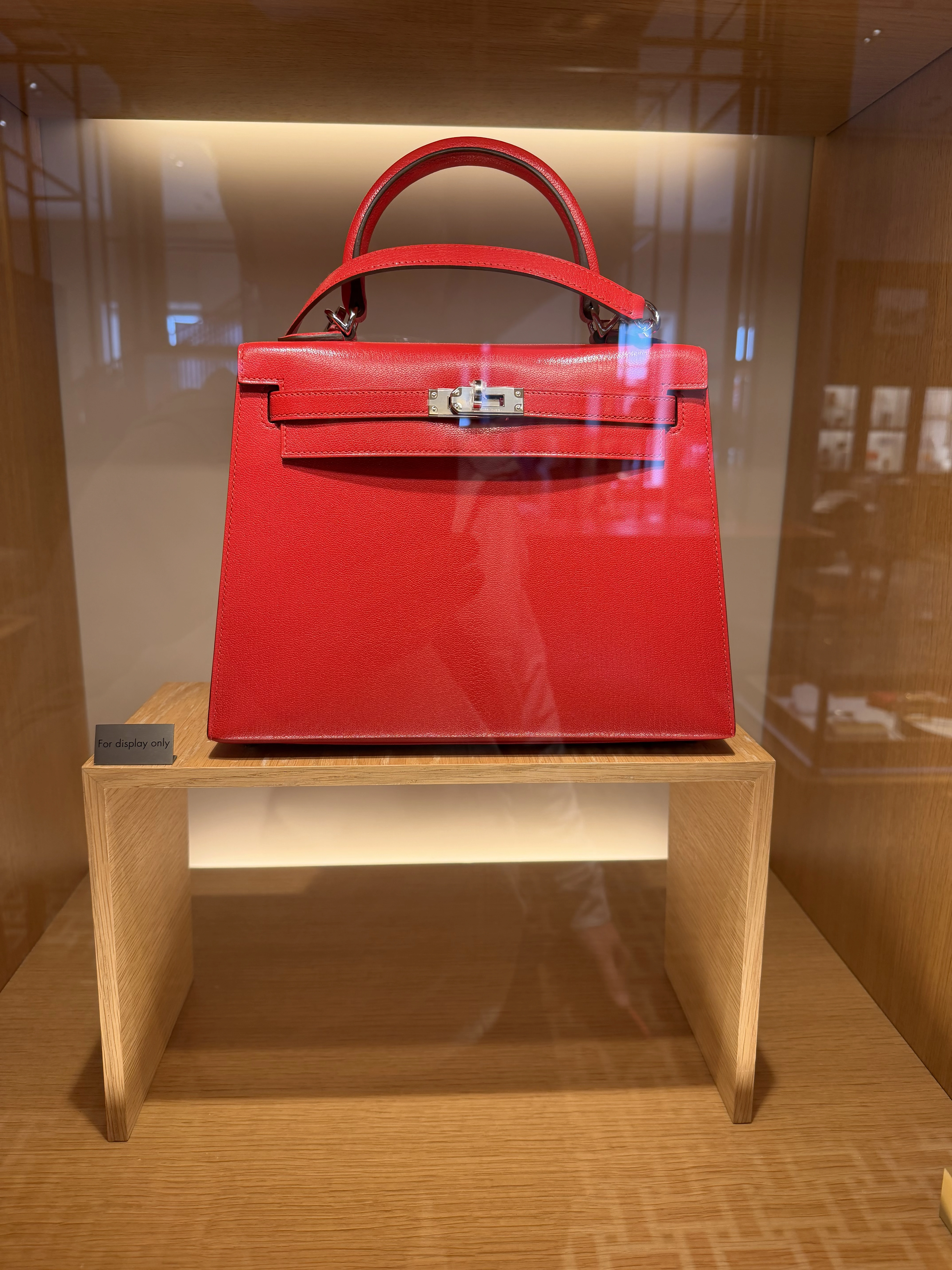 Red Hermès Mini Kelly Sellier displayed behind glass at the San Francisco boutique